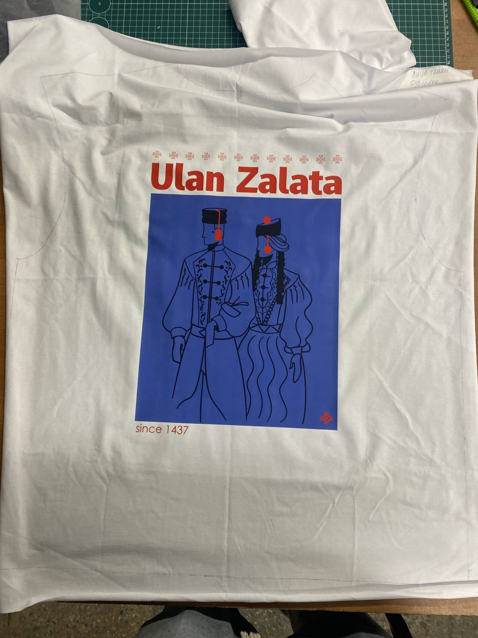 Печать по крою: принт Ulan Zalata на белой ткани, контур будущей футболки размечен до пошива